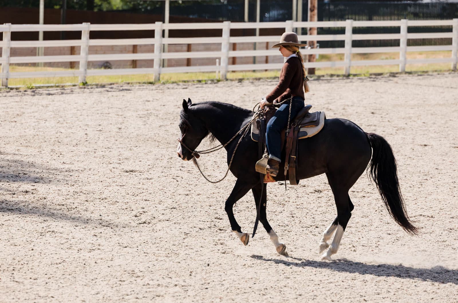 Lili rides toward the camera in a sunlit arena